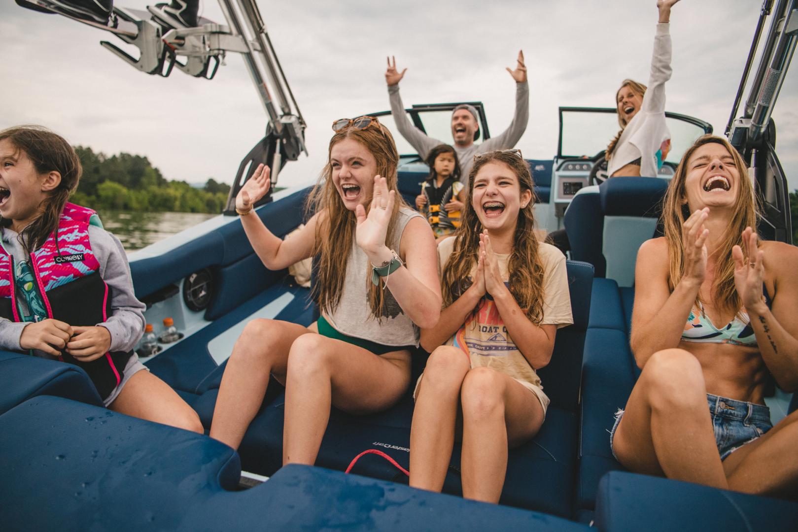 A Family laughing and clapping on their Mastercraft Tow-Boat with blue interior
